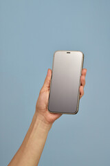 woman holding smartphone with blank screen isolated on blue background