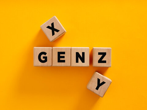 Wooden cubes composing the acronym gen z with generation x and y aside on yellow background