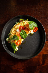 Delicious gourmet omelette topped with smoked salmon, cherry tomatoes, and fresh spinach leaves