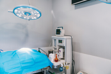 Empty operating room in a veterinary hospital, featuring a surgical lamp, an anesthesia machine, and a covered operating table, ready for a surgical procedure
