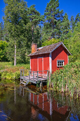 Idyllic red croft with a jetty at a lake in a woodland in the summer © Lars Johansson