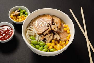 A flavorful bowl of ramen topped with pork, mushrooms, corn, and edamame