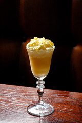 A luscious dessert cocktail topped with whipped cream sits invitingly on a polished wooden surface