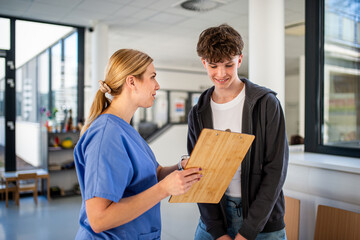 Doctor walking with teenage patient after successful medical procedure in hospital.