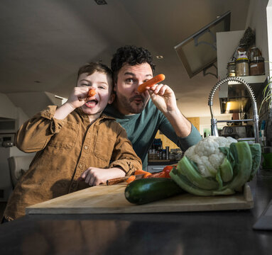 Father and son having fun with vegetables in the kitchen