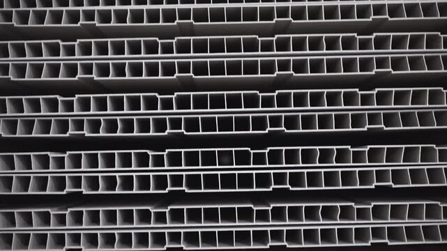 Stacked sheets of PVC profile inner structure in storehouse closeup. Modern plastic construction material manufacturing with extrusion technique