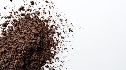 A pile of dark brown powder scattered on a white background, creating a textured, abstract composition
