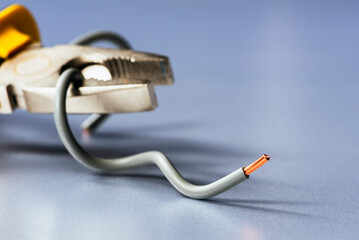 Installation copper electrical wire with pliers on an industrial, metallic grey surface, minimalist composition