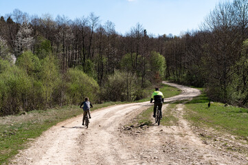 Father and son enjoy a bike ride on a country road, surrounded by lush greenery and trees.