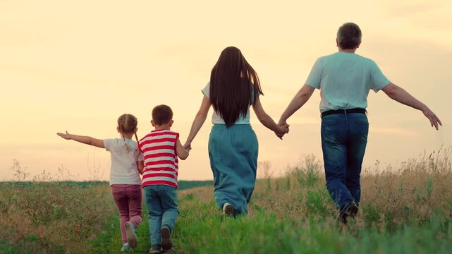 Happy family team, children, parents, run together in sun in park on grass. Concept Family game father mother daughter son fun running. Children dream, mom dad children, holiday, nature. Weekend play
