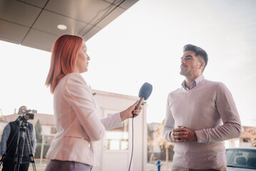 Obraz premium Journalist interviewing businessman holding microphone outdoors