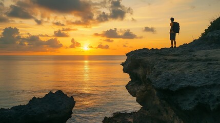Photograph of a lone hiker silhouetted against a vibrant sunset over the ocean.