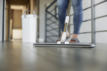 Woman mopping, wiping floor in modern home setting