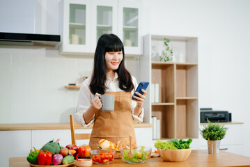 Asian woman preparing healthy food with smartphone in home kitchen. Great for wellness, clean eating, cooking content