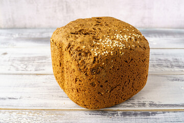 Whole grain bread loaf with sesame seeds and flax seeds on a rustic wooden table, healthy fresh baked snack food, homemade natural delicious bakery product concept.