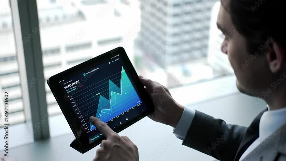 Poster focused male business professional analyzing data trends on a digital tablet while sitting by a larg