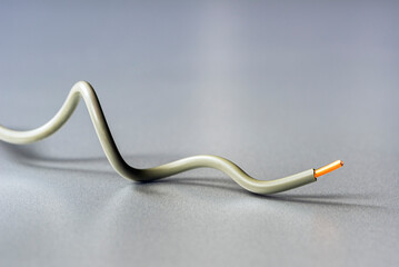 Copper electrical installation wire arranged in a minimalist composition on a grey industrial background