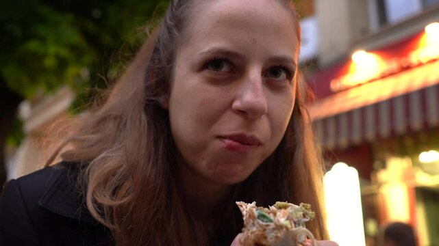 Authentic food moment captured in Bulgaria as a woman eats a falafel duner on the go in Sofia&rsquo;s city center