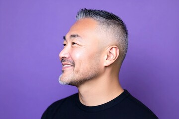 Obraz premium Idea of style for aging men. An elegant midlife gentleman smiling gracefully. Fashionable men's buzz cut haircut - midlife asian man with middle hair. Purple solid background.