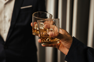 A stylish man holds a glass of whiskey at an upscale bar, enjoying a luxurious indoor celebration with friends and fine alcohol.