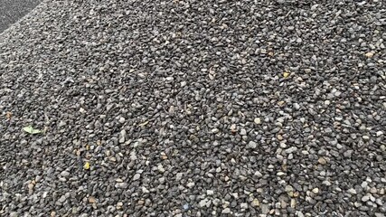 Heaps of small pebbles on wet ground near puddle with tree reflection visible
