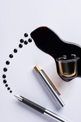 Inchiostro nero versato intorno a un calamaio di vetro con una penna stilografica