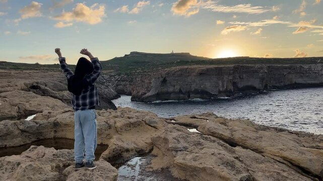 A boy on a rock near the sea. A beautiful sea sunset.