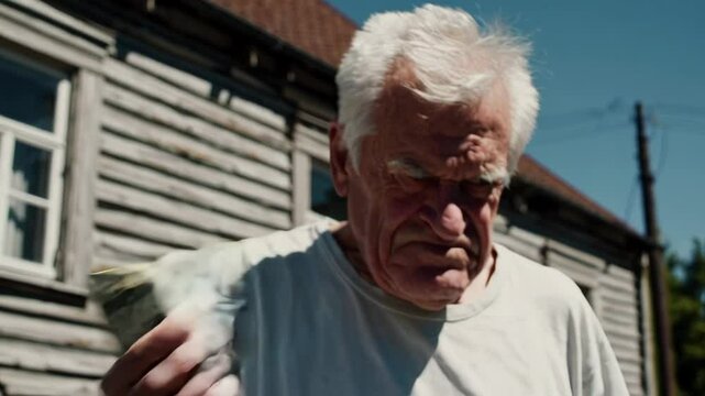 Angry old man holding blurred money