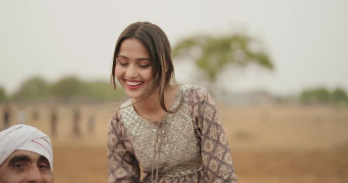 Indian village farmer woman female wear traditional dress smiling sitting on tractor outdoor asian teen age girl daughter talk gossip old aged man driving outside farmland desi life rural area