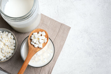 Naklejka na ściany i meble Milk kefir grains on wooden spoon and glass of kefir