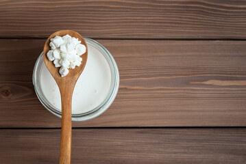Milk kefir grains on wooden spoon and jar of kefir