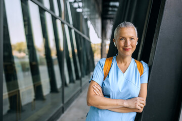Nurse standing confidently outdoors near a modern building during daylight, showcasing a...