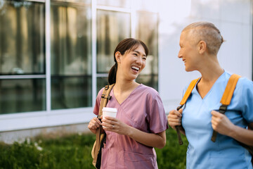 Two nurses share a joyful moment outdoors wearing scrubs in a sunny environment
