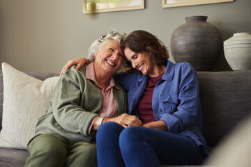 Loving and happy mother embracing adult daughter on couch at home