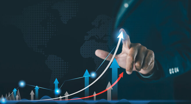 A businessperson interacts with a digital graph showing upward financial growth, with global data and rising arrows. - Powered by Adobe