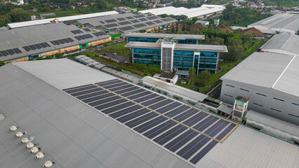 Rows of solar panels installed on the rooftop of a factory, capturing sunlight efficiently as part...
