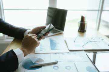 A businesswoman sits at a desk in a corporate office, analyzing financial documents, charts, and...