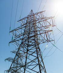A tall power tower with many wires and a clear blue sky in the background