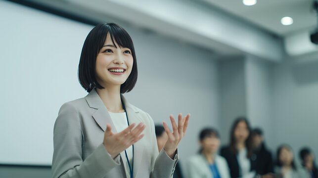 講演会で身振り手振りを交え話すスーツの女性