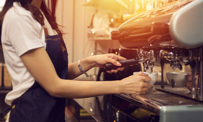 Hands of barista making coffee with espresso machine. Barista woman with apron preparing coffee for customer in her small business