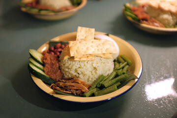 A plate of nasi lemak or rice cooked in coconut milk. Vegetables, chilli paste, anchovies and cucumber are added to this Malay dish, popular in South East Asia.