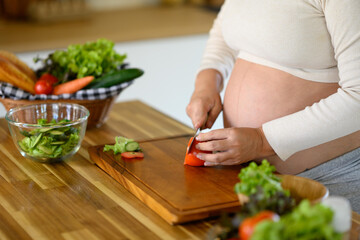 Pregnant woman preparing healthy meal in kitchen