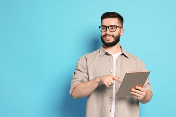 Man using tablet on light blue background, space for text