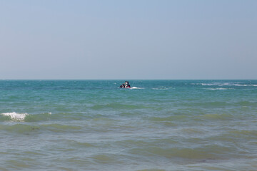 Fototapeta premium A person rides a jet ski on the calm waters of the Persian Gulf near Bushehr, Iran, under a clear sky.