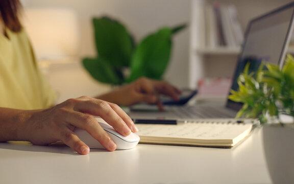 Close up woman hand click on wireless computer mouse working online on laptop computer at home surfing internet searching information internet network digital technology.