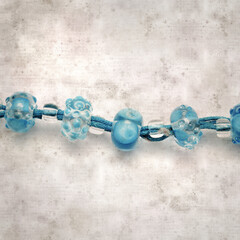 textured stylish old paper background, square, with a simple necklace of blue and transparent glass...