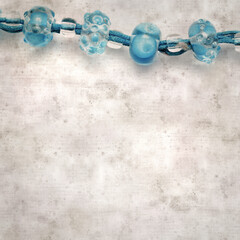textured stylish old paper background, square, with a simple necklace of blue and transparent glass...