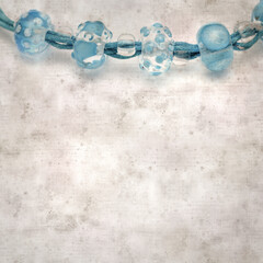 textured stylish old paper background, square, with a simple necklace of blue and transparent glass...
