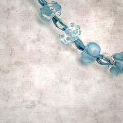 textured stylish old paper background, square, with a simple necklace of blue and transparent glass...