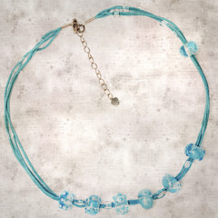 textured stylish old paper background, square, with a simple necklace of blue and transparent glass...